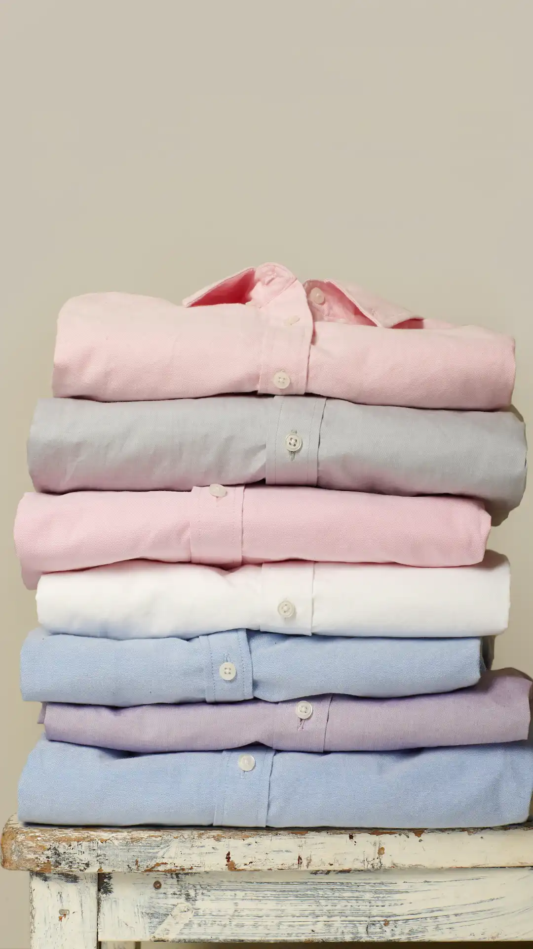 folded assorted-color collared button-up shirts on white wooden table