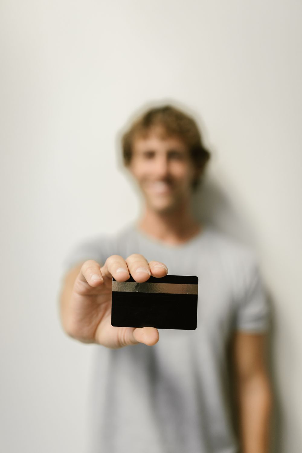 Blurred image of a man holding a credit card, indoor setting with selective focus.